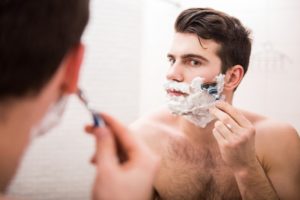 Handsome-young-man-is-shaving-his-face-and-looking-at-the-mirror-805x538